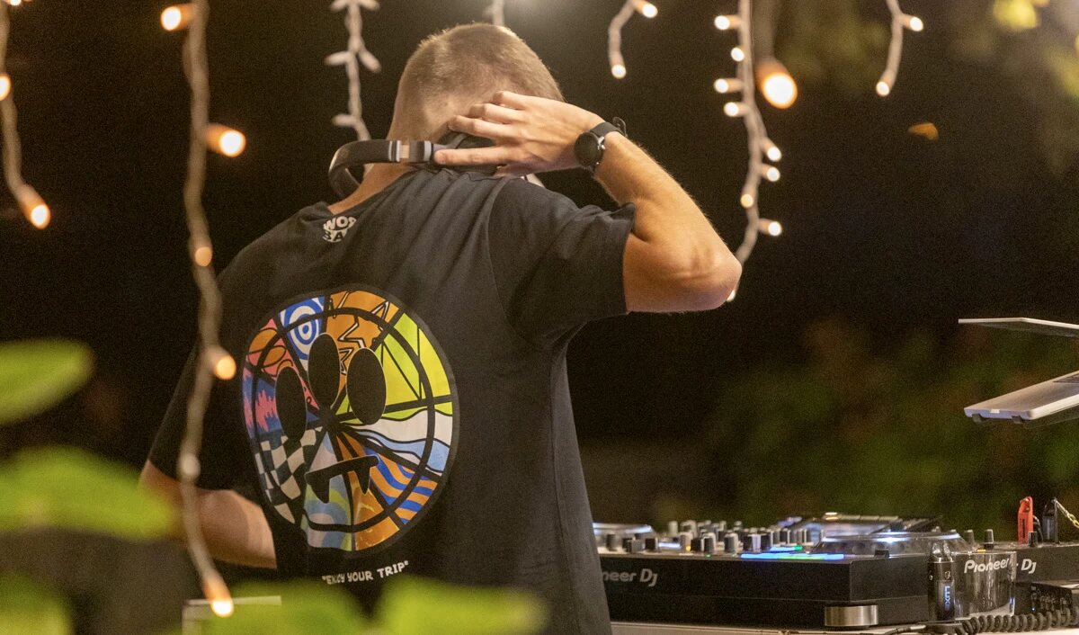 Davide DJing, seen from behind at a Pioneer mixer under warm lights